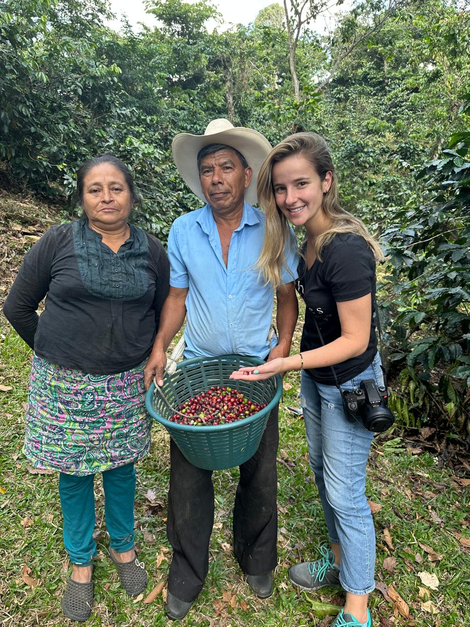 Gabriela Rodas with two coffee producers holding a basket of freshly picked cherries